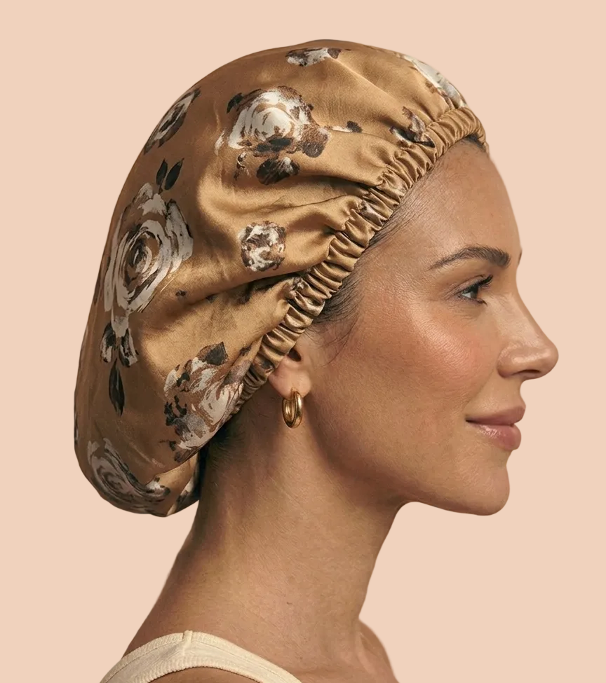 A woman in profile wearing a silk bonnet with a floral print in beige, brown, and white, set against a solid beige background.